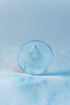 Close-up of an Ethereum cryptocurrency coin against a soft blue backdrop.
