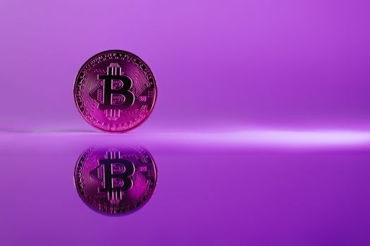A striking image of a Bitcoin coin reflecting on a glossy surface against a vibrant purple background.