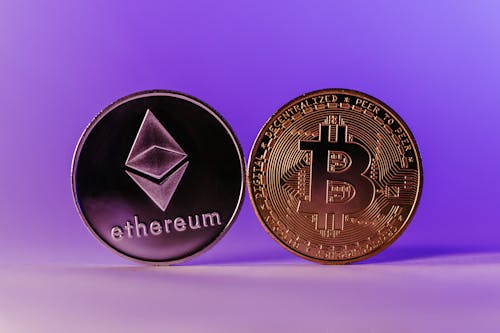 Bitcoin and Ethereum Coins Standing against a Purple Background