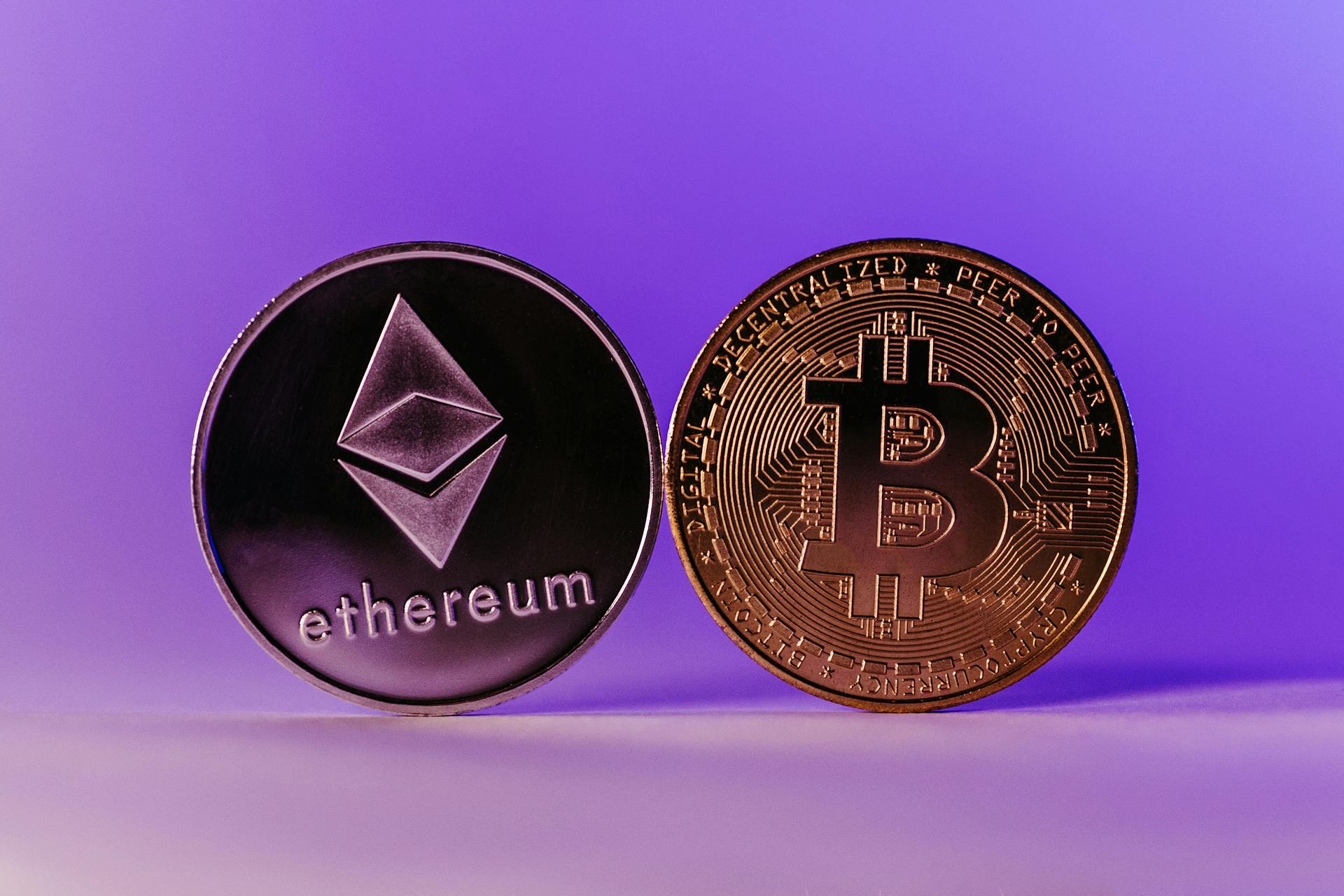 Close-up of Ethereum and Bitcoin coins symbolizing cryptocurrency and blockchain technology against a purple backdrop.