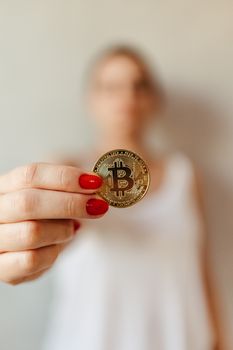 Person holding a bitcoin with red nails in a close-up shot.