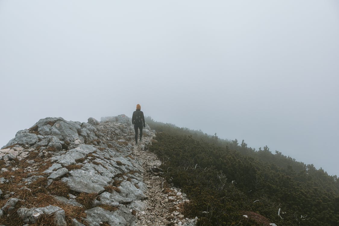 Person Hiking in Fog-Shrouded Mountains