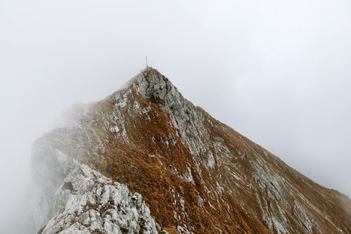 Free A dramatic mountain peak shrouded in fog and mist, creating a mystical landscape view. Stock Photo