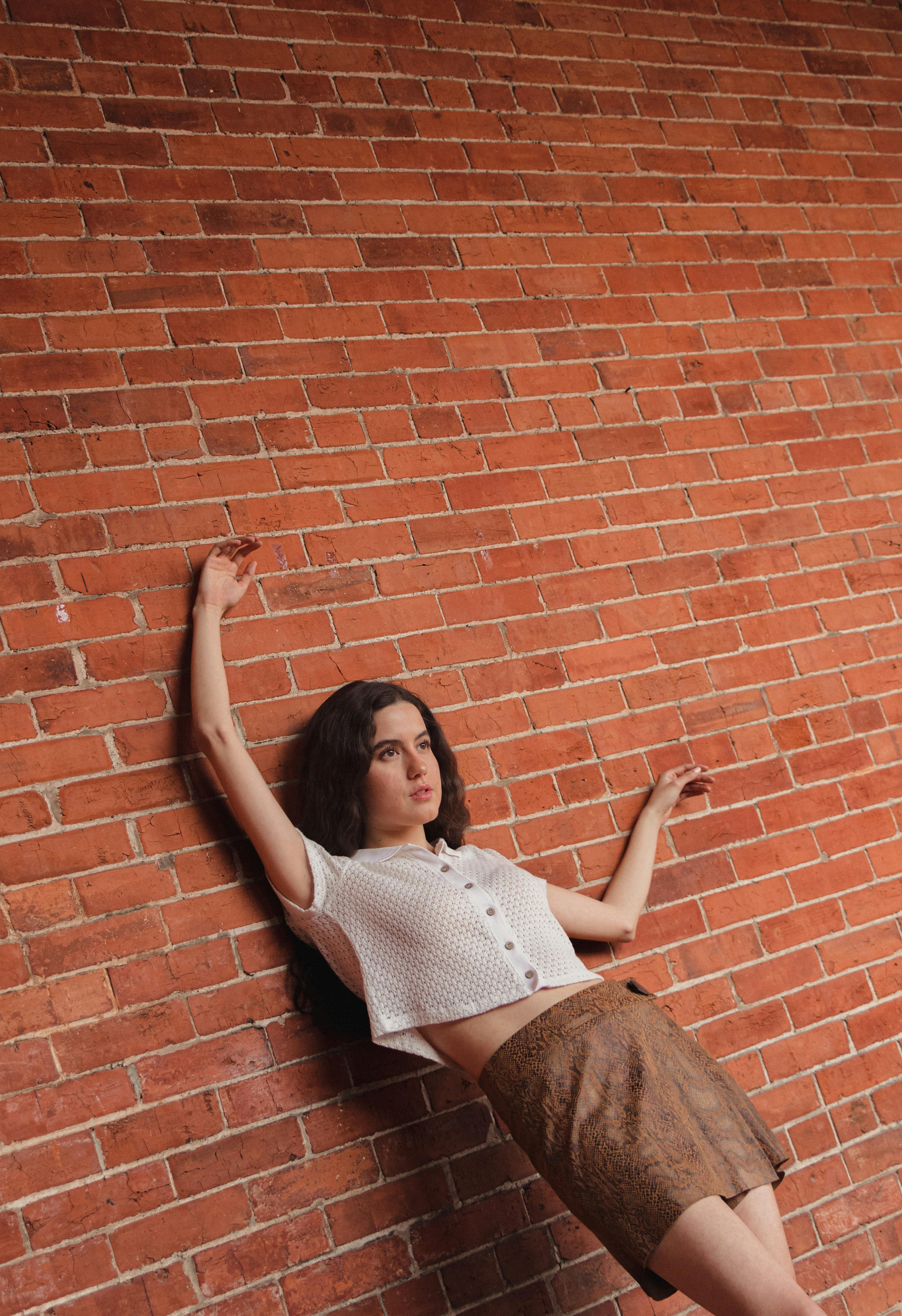 Young woman leaning against a brick wall. Casual fashion outdoors in Mexico City.