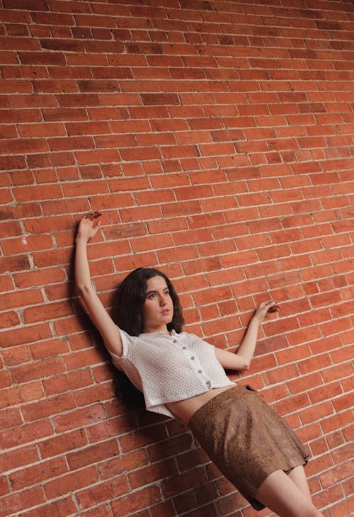 Young Woman Leaning against a Brick Wall 