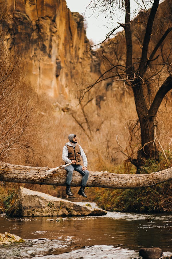 Bearded Man in Hoodie Sitting on Fell Tree Trunk