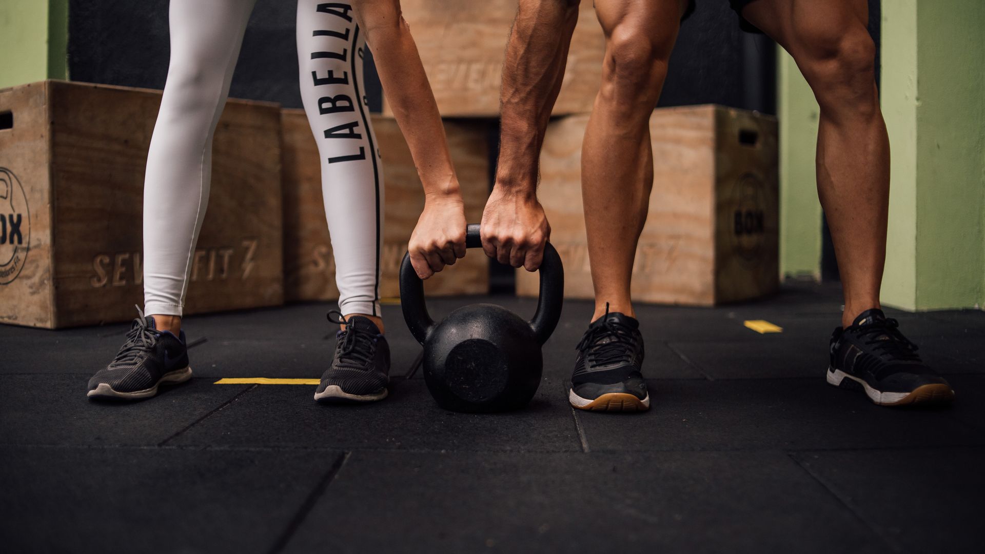 Modafinil Workout Enhancement: Unleash Your Peak Performance A man and woman engaging in CrossFit training with a kettlebell at an indoor gym in Brazil — modafinil workout enhancement