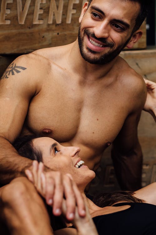 Photograph of a Shirtless Man Smiling with a Woman