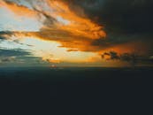 日落色彩鲜艳，照亮了山地景观上的乌云，令人惊叹