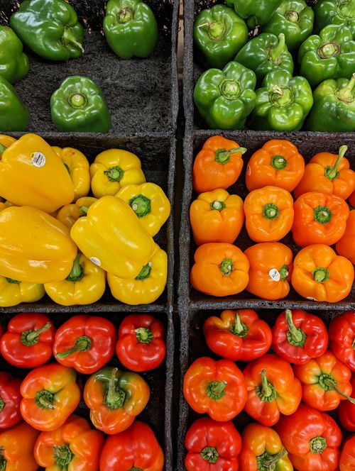 Free Vibrant display of green, yellow, orange, and red bell peppers at a market. Stock Photo