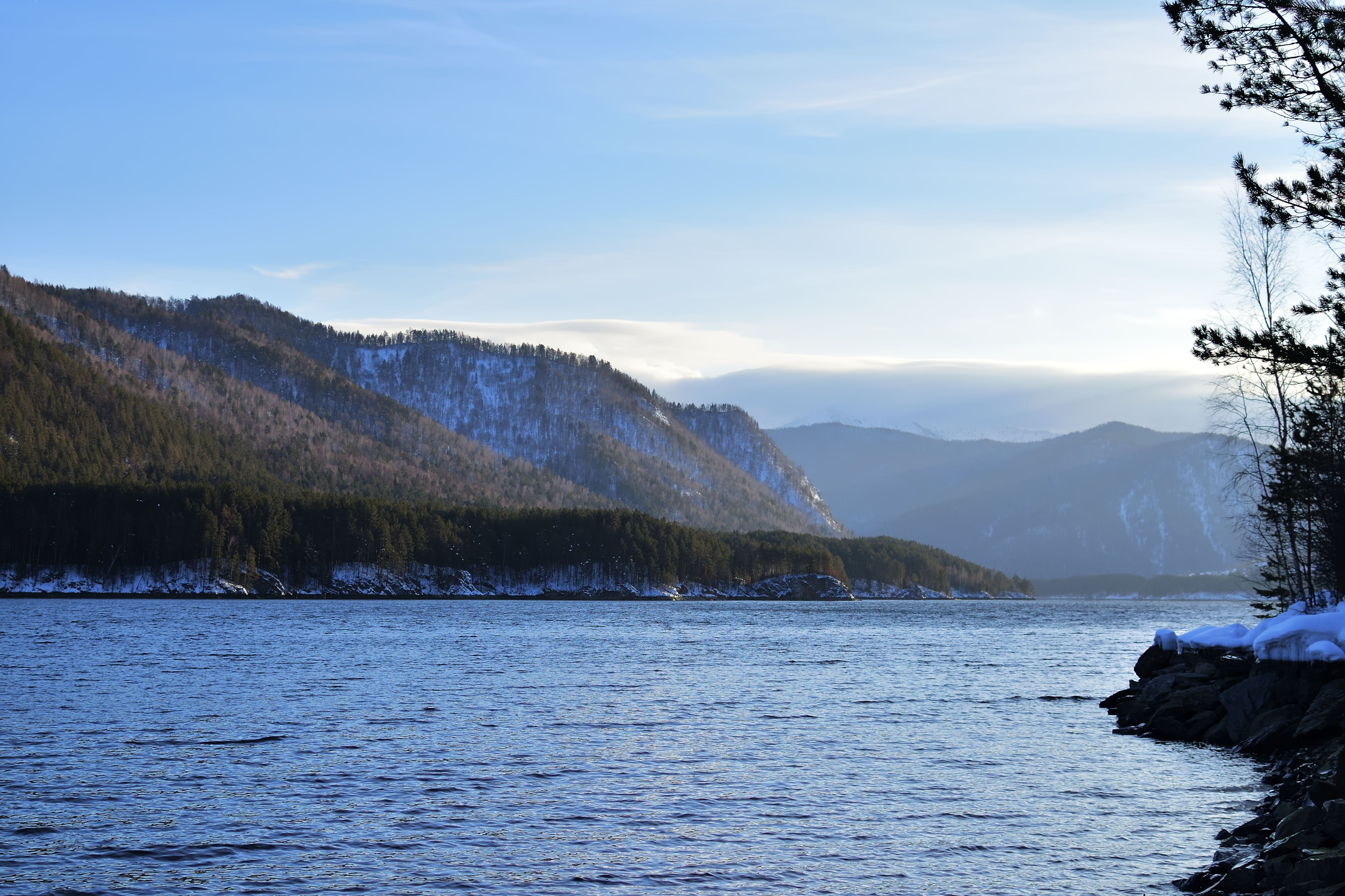 Tranquil mountain lake with snow-capped peaks under a clear blue sky, showcasing serene nature.
