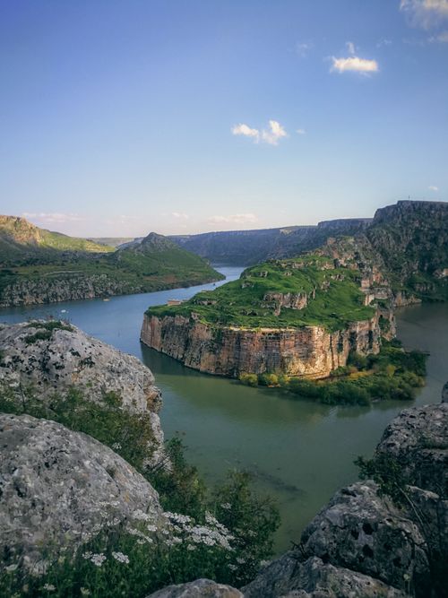 Free Breathtaking view of a river winding through a lush canyon with towering cliffs and a clear blue sky. Stock Photo