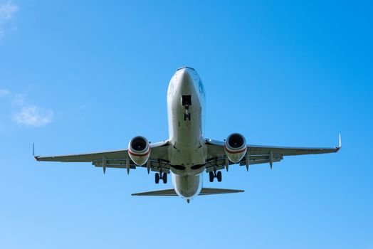 A low-angle shot of a Boeing airplane taking off, set against a clear, vivid blue sky.