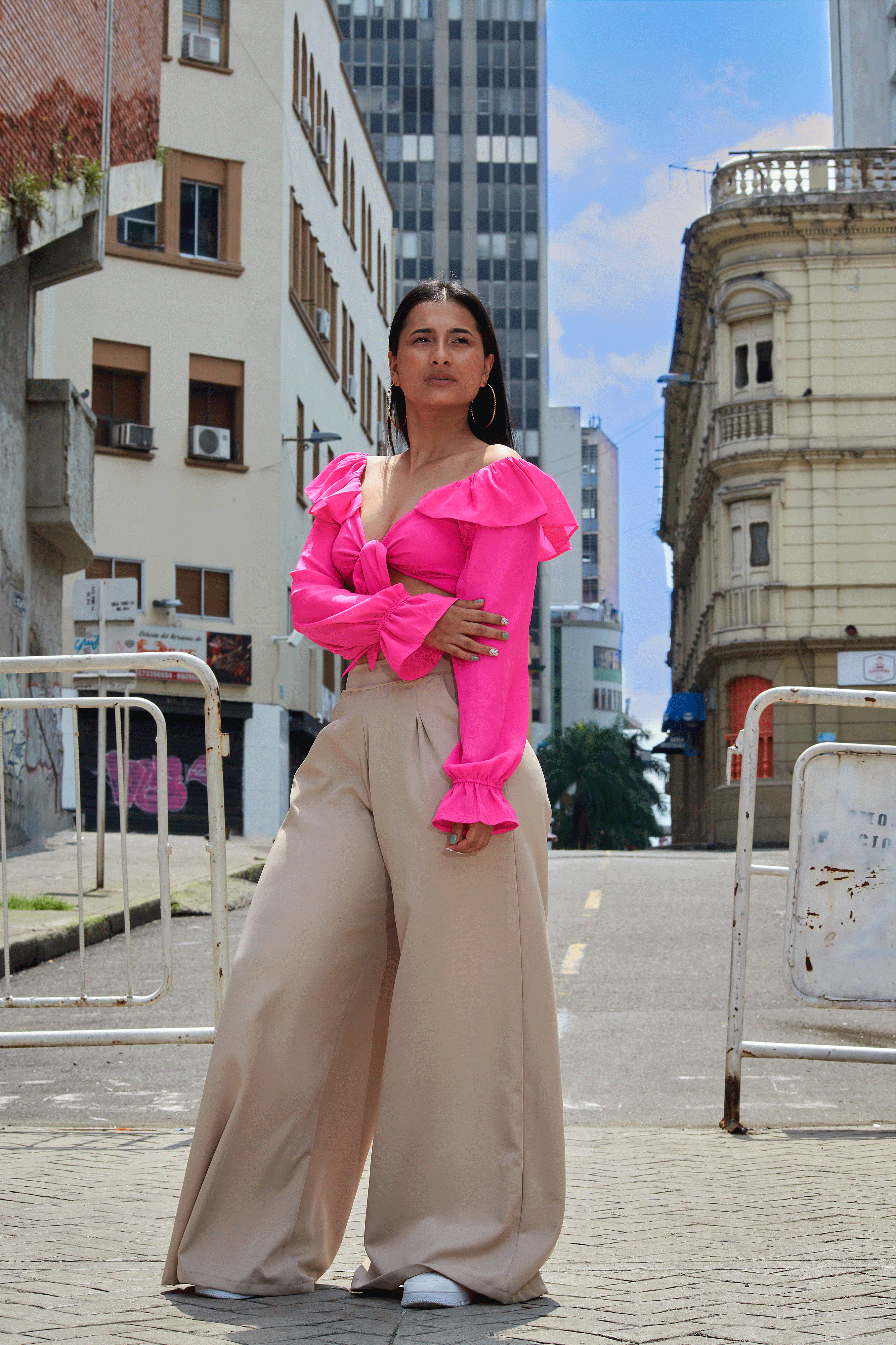 Mulher estilosa na cidade usando um traje vibrante, posando confiante na rua com um fundo arquitetônico.