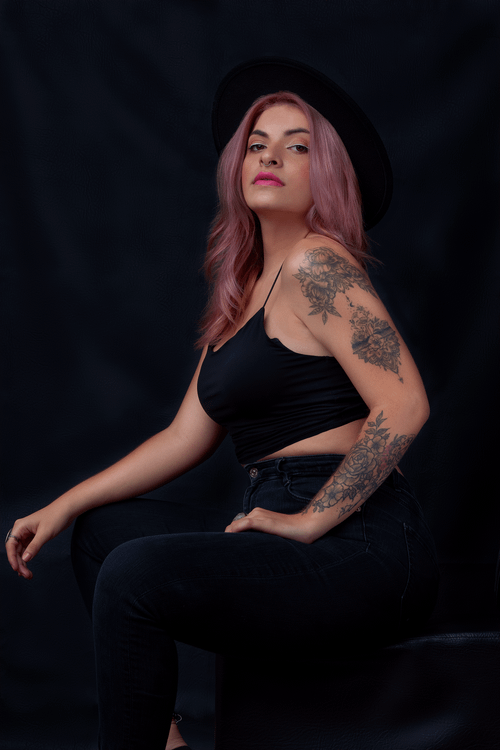 Free Portrait of a fashionable woman with tattoos and colored hair, captured in a studio setting. Stock Photo