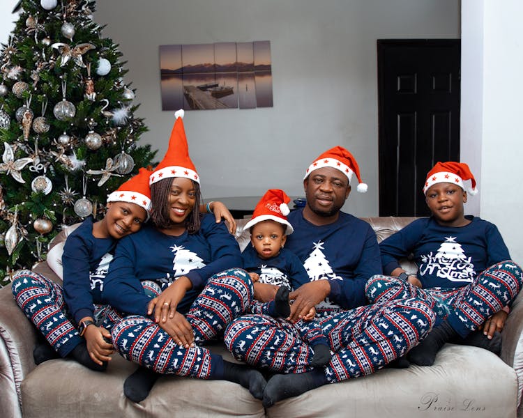 A Happy Family Wearing Santa Hat And Blue Pajamas Photo