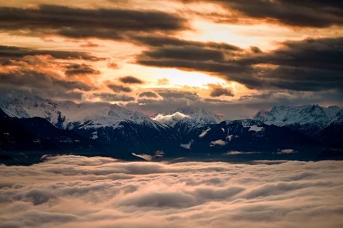 Free A breathtaking view of snow-capped mountains at sunrise over a sea of clouds in Crans-Montana, Switzerland. Stock Photo