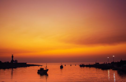 Beautiful sunset over Daman's waterfront with boats silhouetted against the dramatic sky.