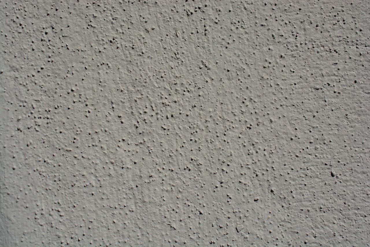 a close up view showcasing the intricate texture of a gray stucco wall