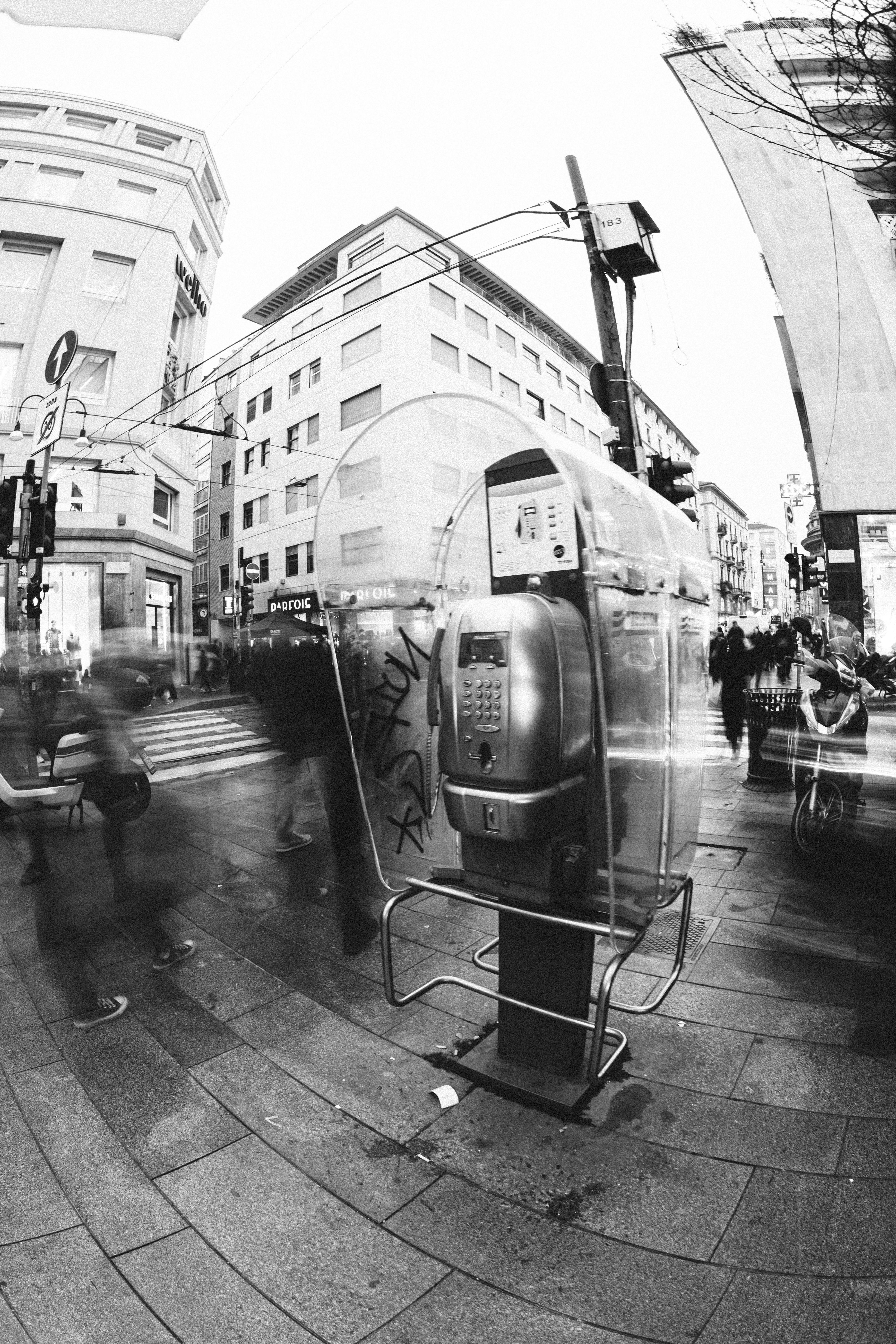 Vintage cityscape captured in black and white with a payphone and blurred motion of people.