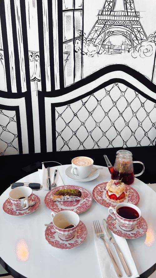 Free Charming tea setup with desserts, cappuccino, and tea on a white table, perfect for a cozy teatime. Stock Photo