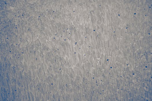 Abstract blue and white wall texture with scattered spots, ideal for creative backgrounds.