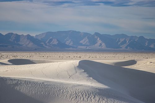 Free Expansive view of white sand dunes against distant mountains under a serene blue sky. Stock Photo