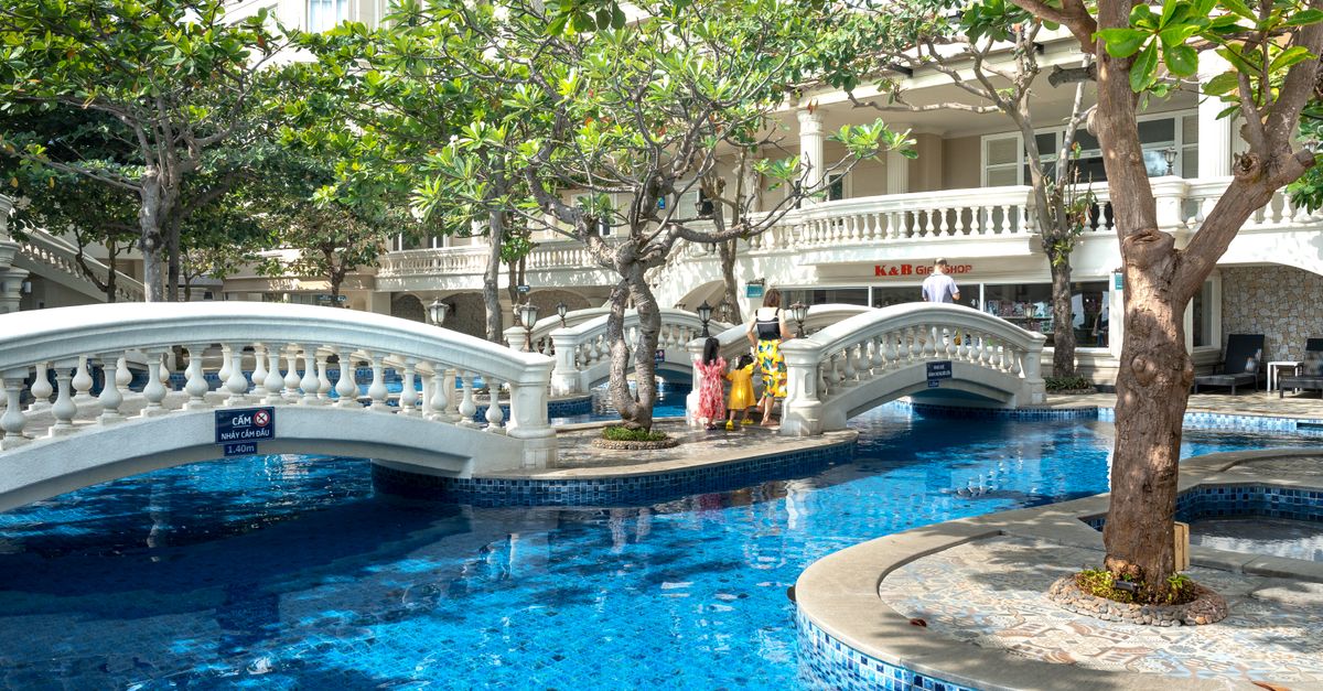 A beautiful hotel pool with stone bridges and lush greenery, perfect for relaxation.
