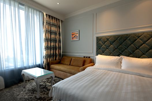 Luxurious hotel room featuring a plush bed, sofa, and patterned curtains creating a cozy ambiance.