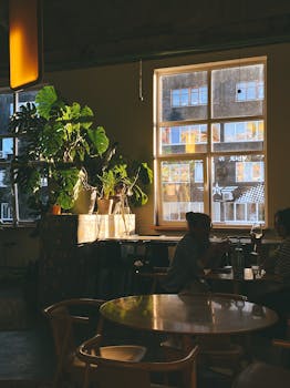 Warm café atmosphere with plants and silhouettes in evening light.
