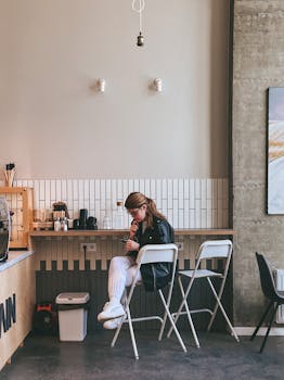 A woman enjoys a quiet moment in a stylish cafe in Minsk, Belarus, sitting at a high bar counter.