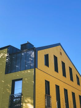 A modern yellow building with geometric architecture under a clear blue sky.