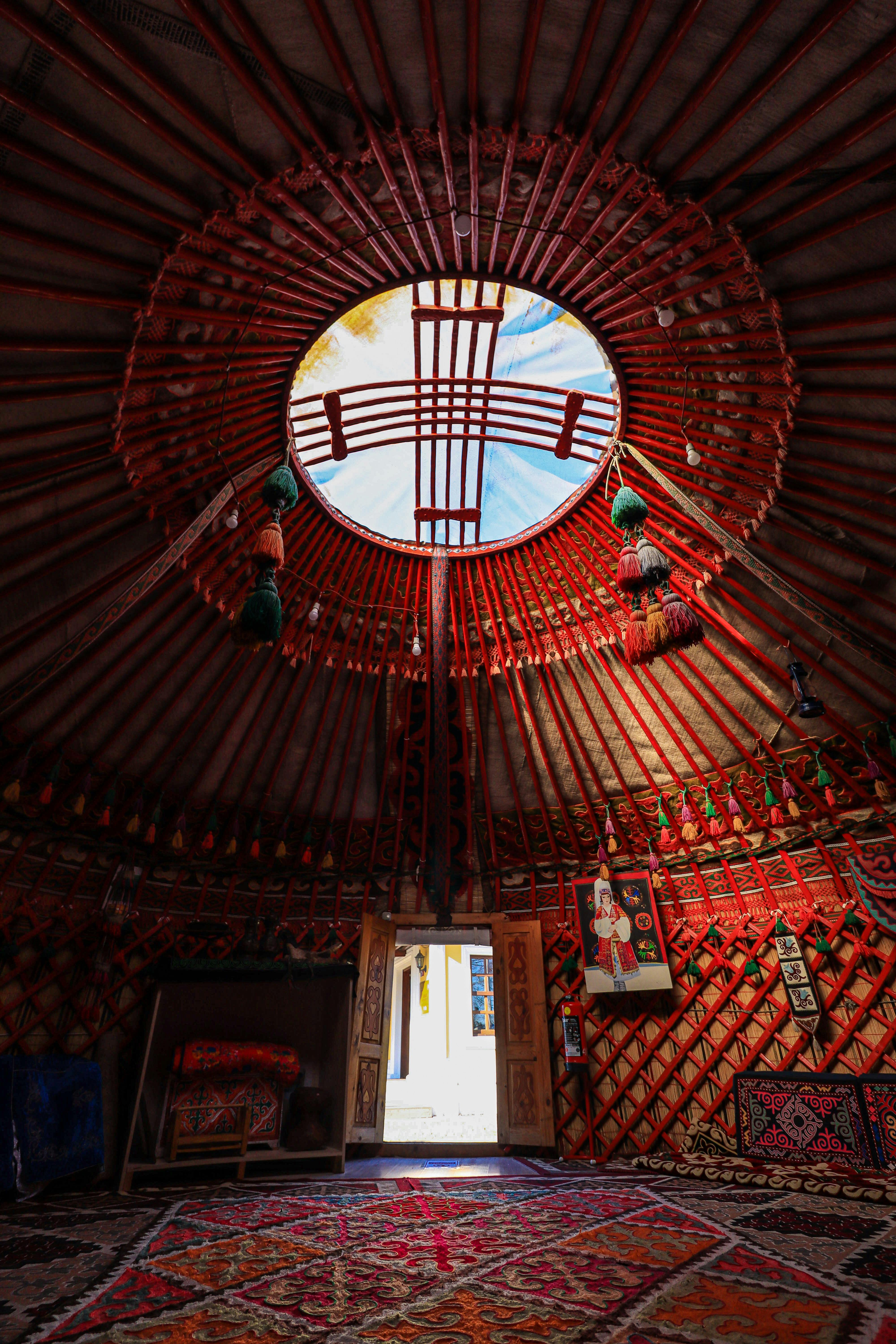 Vibrant interior of a traditional yurt showcasing intricate patterns under a bright skylight.