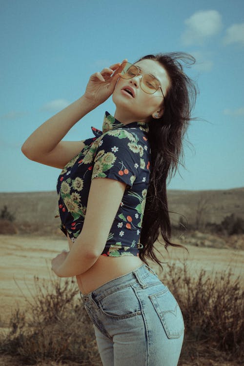 Woman Wearing Floral Crop Top Holding Sunglasses