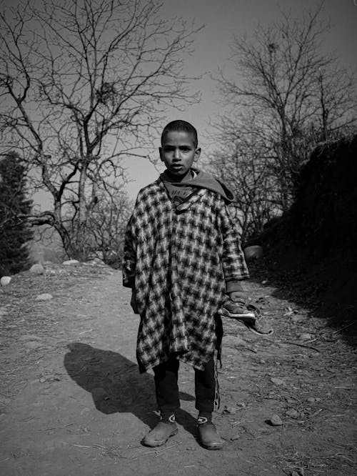 Boy in Cloak in Village in Black and White