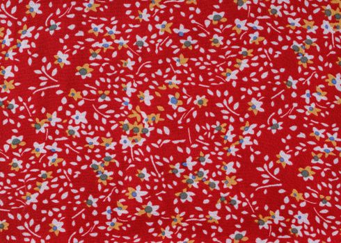 Colorful floral pattern featuring small flowers on a vivid red fabric background.