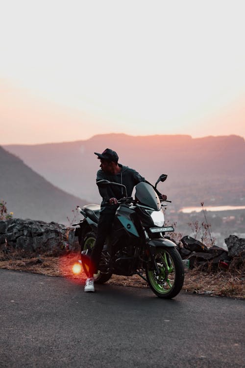 Man Traveling on Bajaj Pulsar NS200 Motorcycle at Sunset on Mountain Road