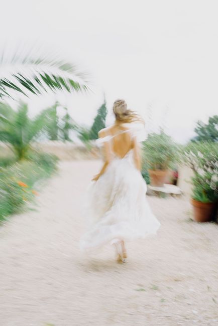 Artistic blur of a woman in a white dress running along a pathway with greenery.