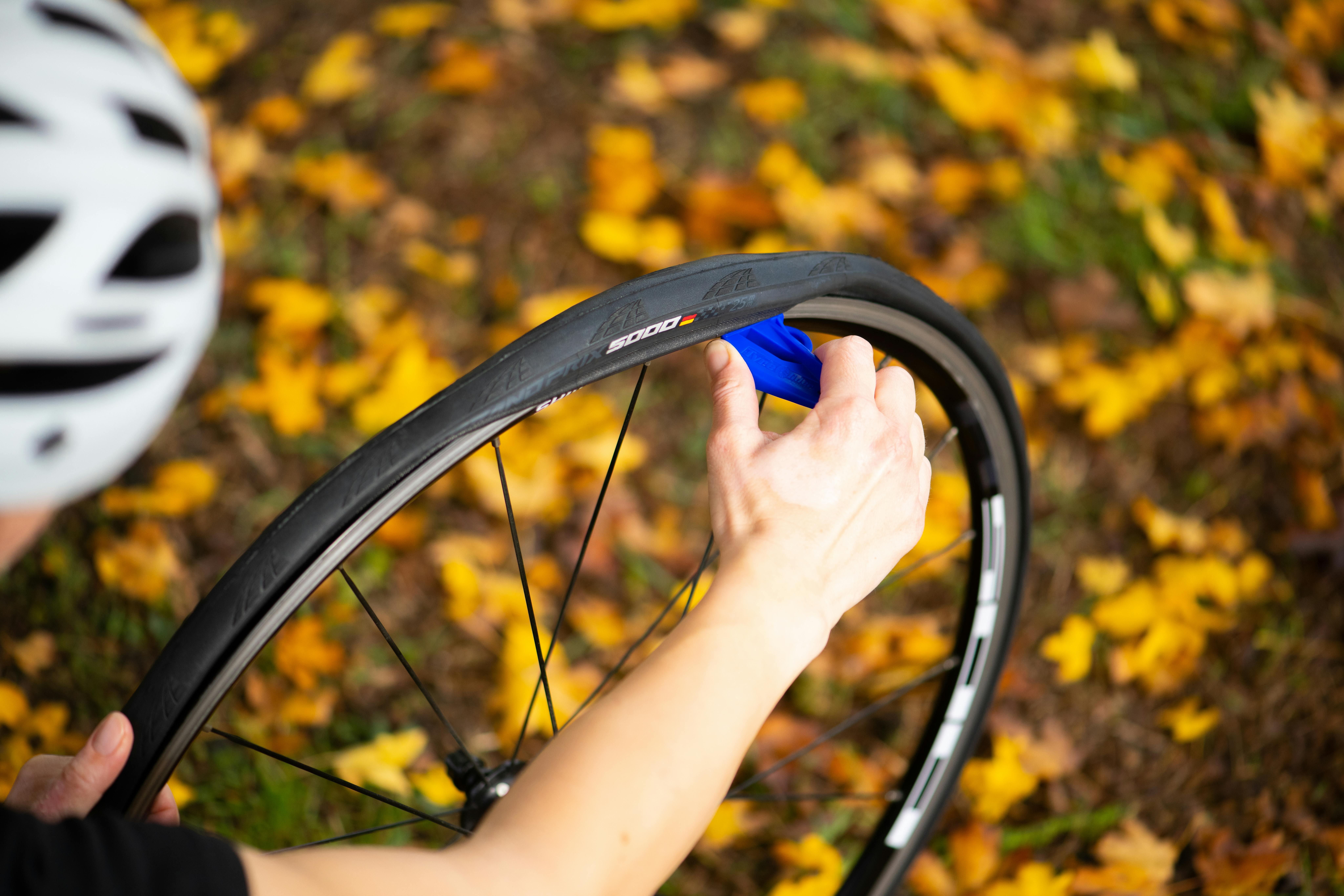 Free Biker fixing a flat bike tire in a park with autumn leaves. Close-up shot. Stock Photo