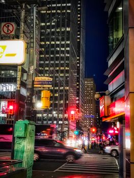 Vibrant nighttime street scene in downtown Toronto with bustling traffic and city lights.