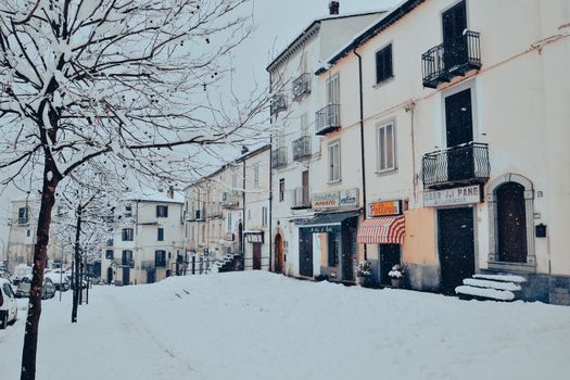 Charming urban street blanketed in snow, featuring quaint residential buildings in winter.