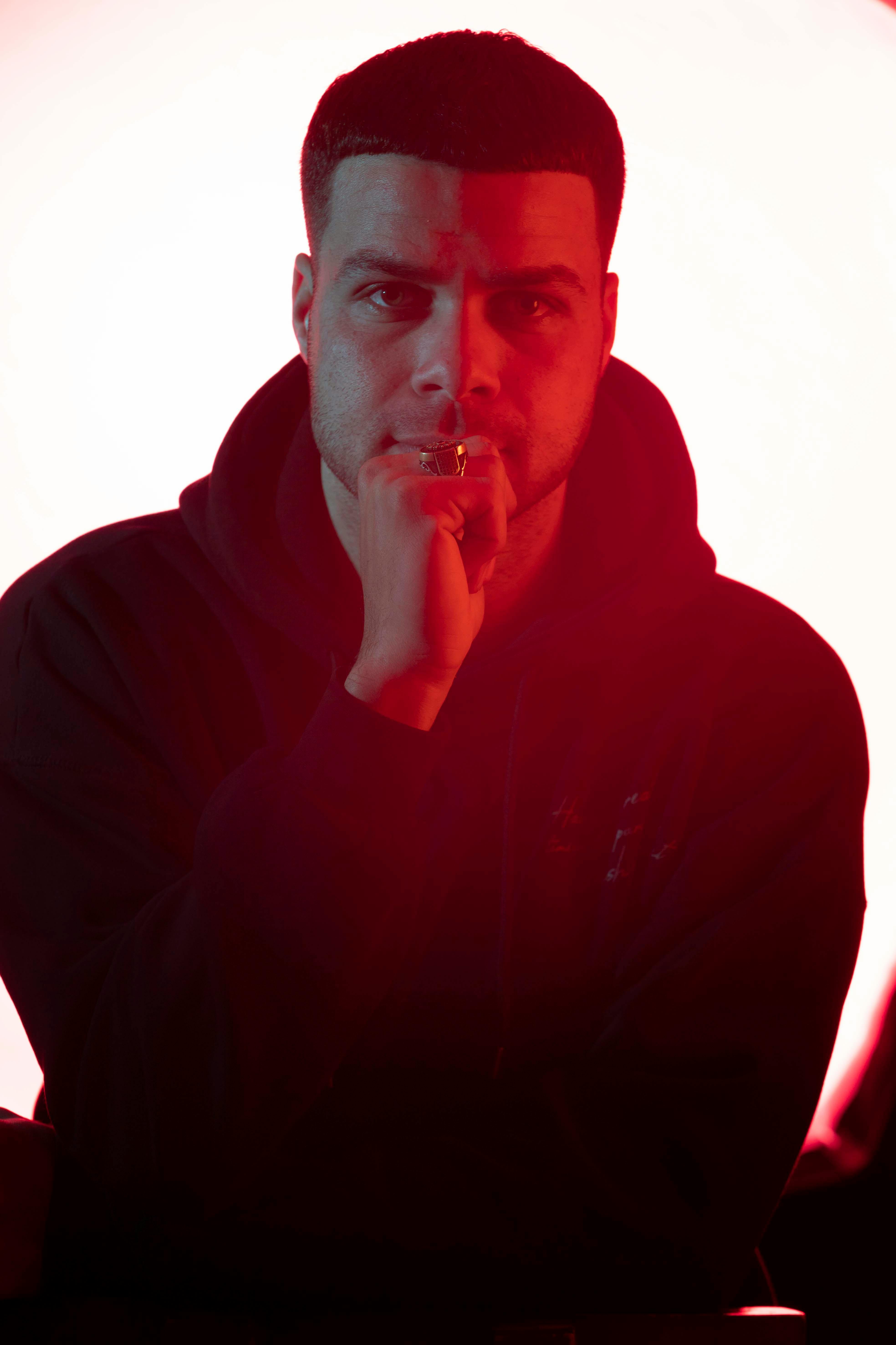Portrait of a thoughtful man in red backlighting, capturing a moody and introspective atmosphere.