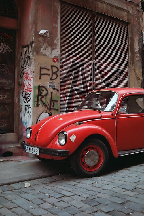Red Volkswagen Beetle Parked Outside an Abandoned Building