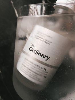 Close-up of The Ordinary hyaluronic acid skincare product submerged in cold water glass.
