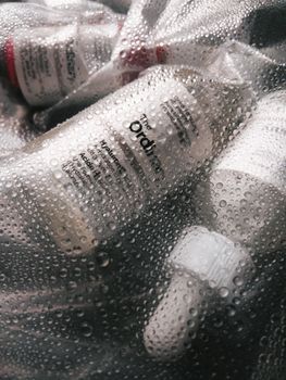 Moisture-covered skincare products including serum and exfoliator bottles in focus.