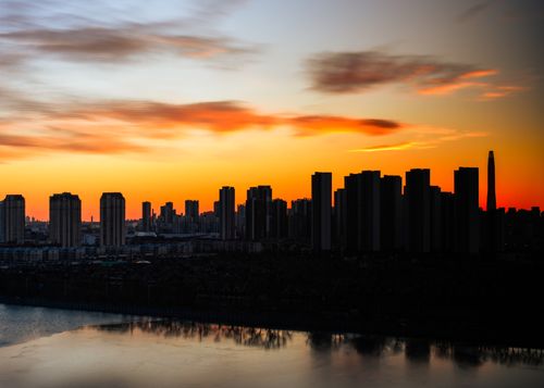 Free Dramatic city skyline silhouette against a vibrant sunset sky. Stock Photo