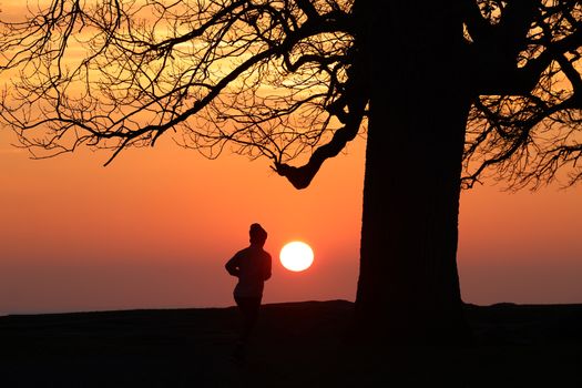 A runner is silhouetted against a stunning sunrise in Stamford, CT, adding a peaceful yet dynamic feel.