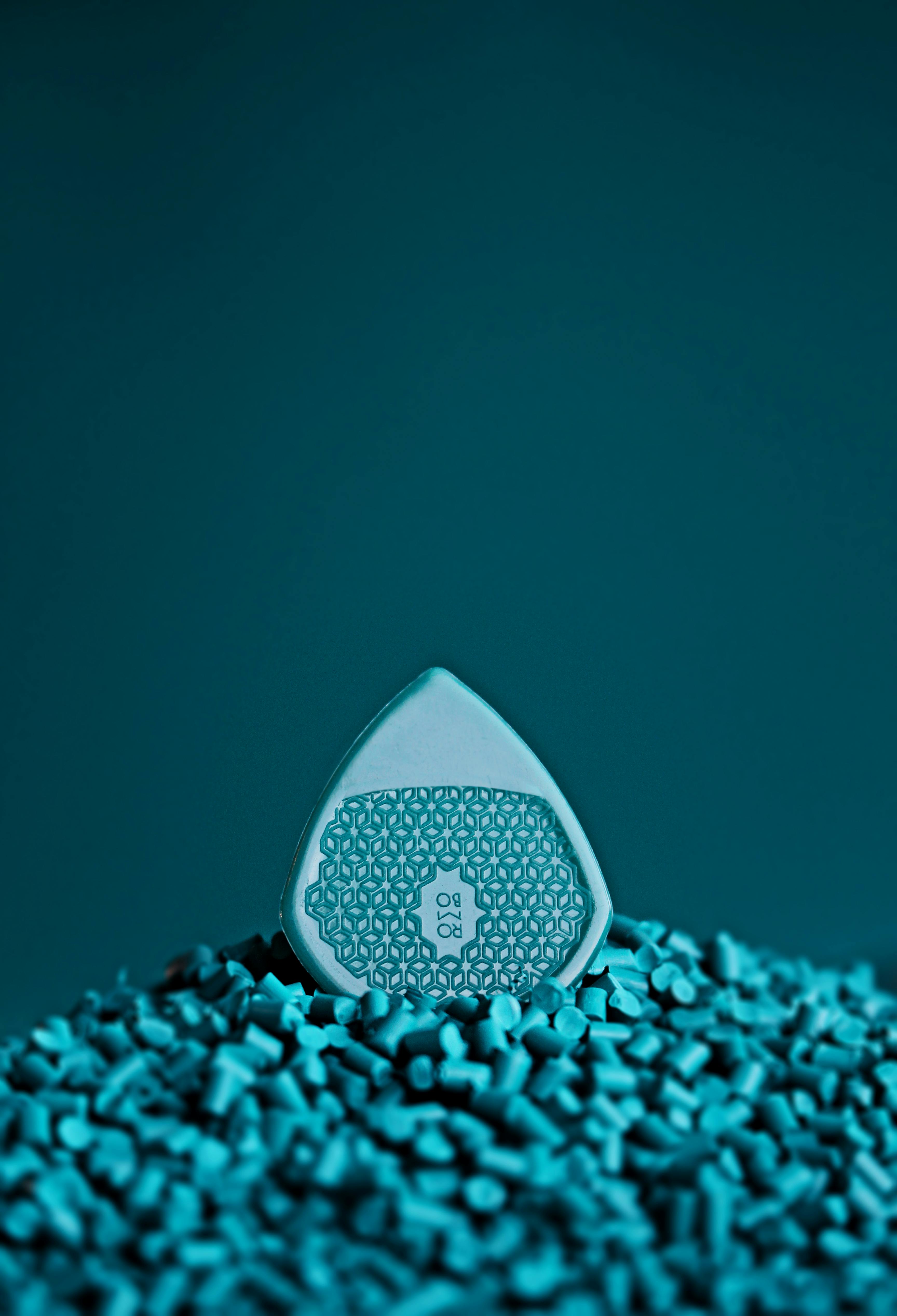 Close-up artistic shot of a blue guitar pick on a vibrant background.