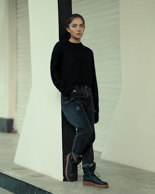 A Woman in Black Sweater Leaning on the Post
