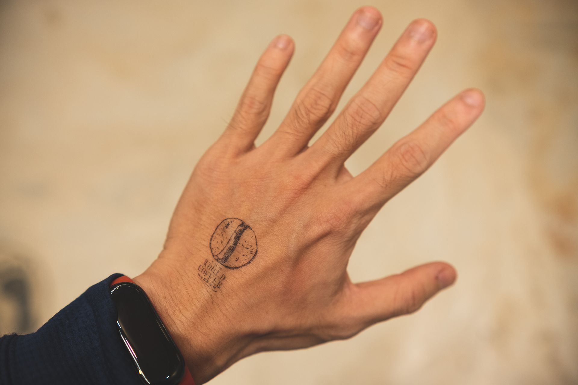 A close-up image of a tattooed hand showing a unique design and a smartwatch on the wrist.